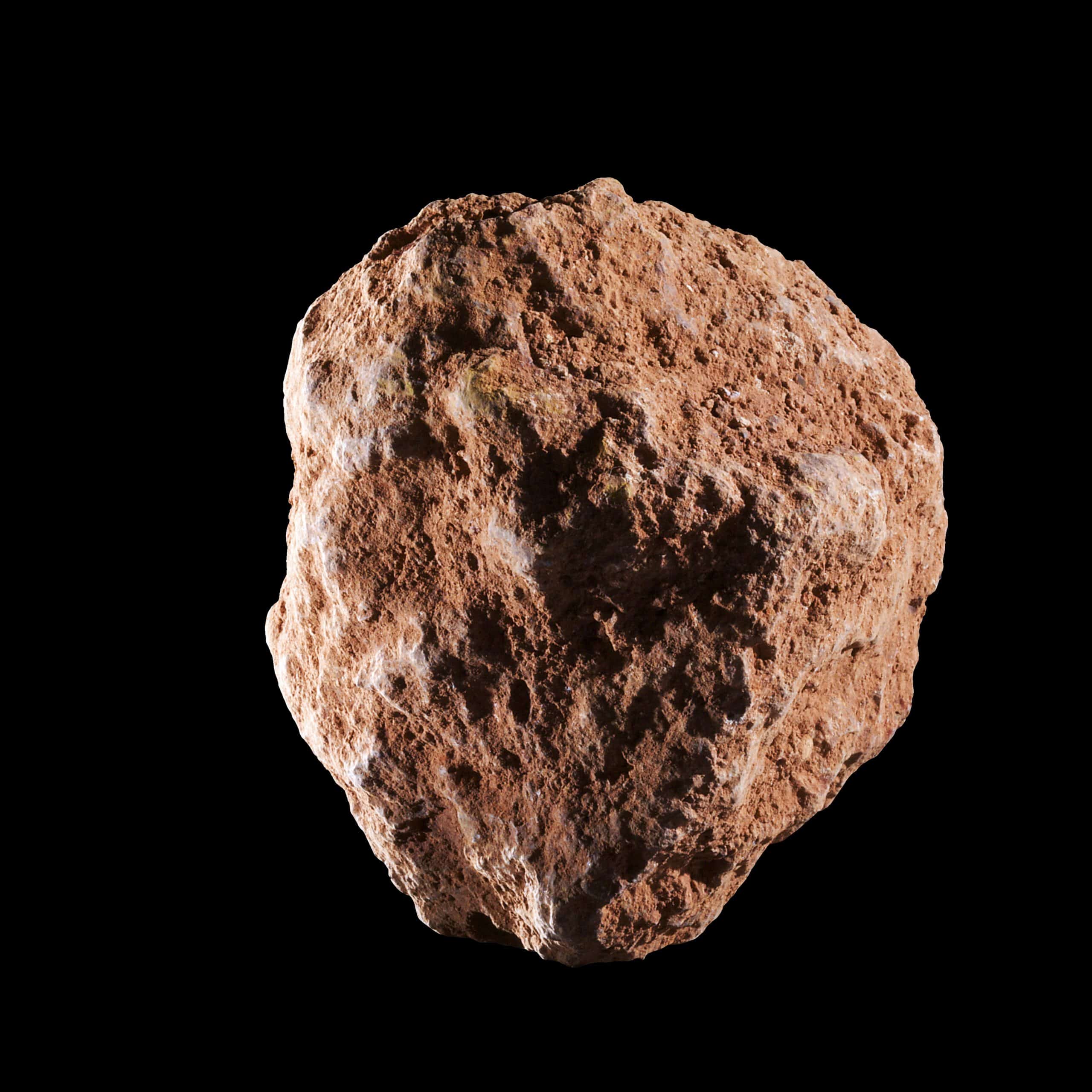 A rough-textured, irregularly shaped brown rock is centered against a black background. Its surface is uneven with numerous small protrusions and indentations, highlighting its natural, unpolished appearance, much like the unrefined state of aluminium before it undergoes.